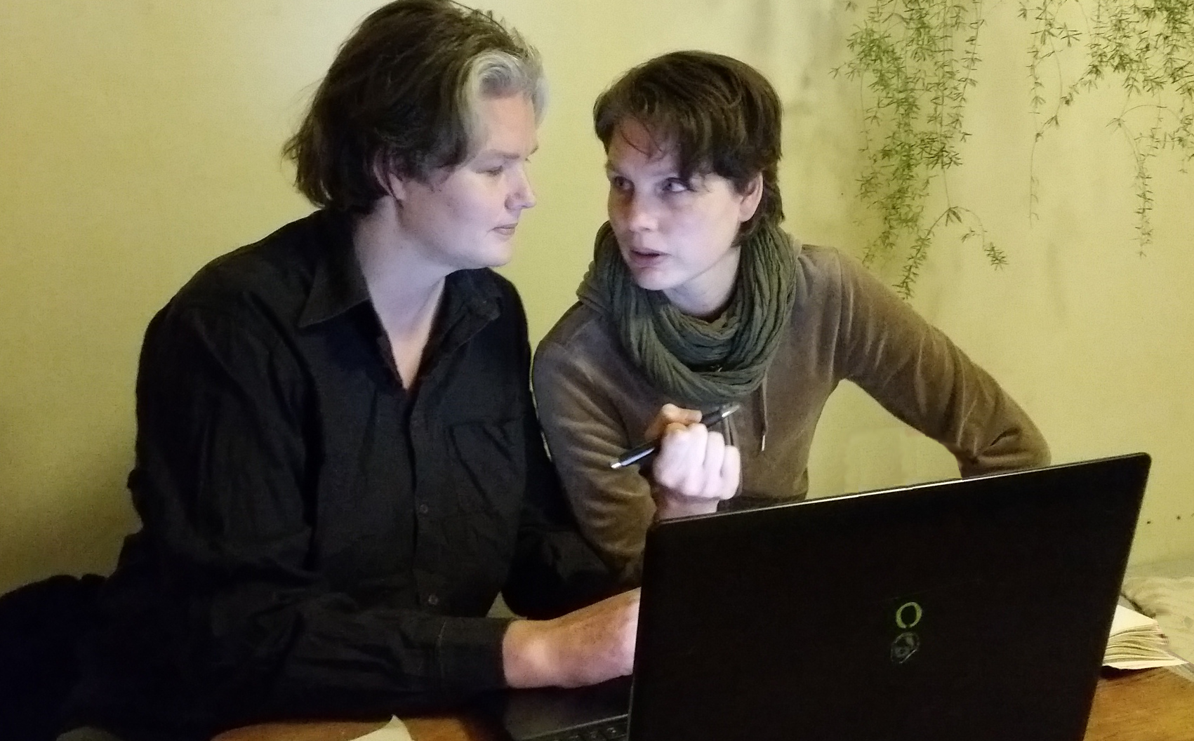 Stina och Eli diskuterar i ljuset från en laptop.